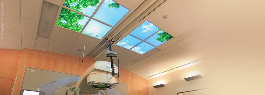Radiotherapie ruimte met verlichte foto's van wolken en bomen aan het plafond. Een aangename afleiding voor patiënten.
