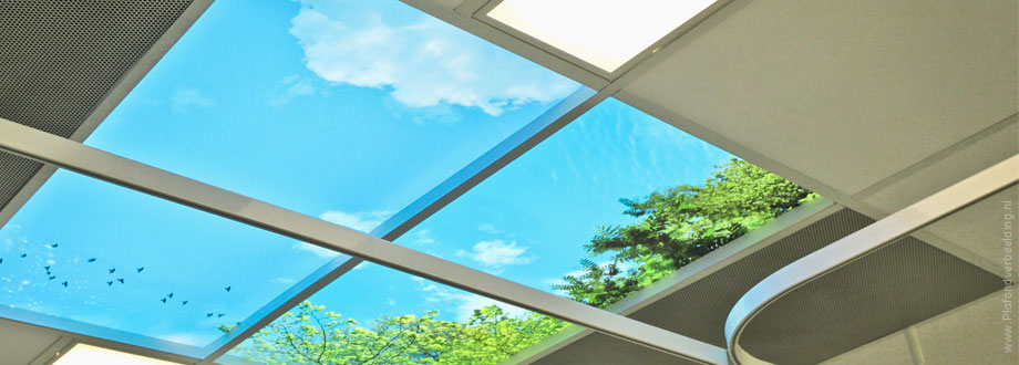 Systeemplafond met uitzicht op natuur. Het plafond van een zorginstelling inrichten met foto's van wolken, bomen, blauwe lucht en verlichting met daglicht simulatie.  